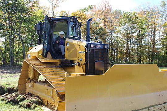 woman with glasses and hardhat operating a bulldozer 